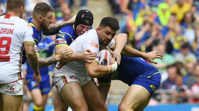 Mickael Simon of Catalan Dragons is held by the Warrington Wolves defence