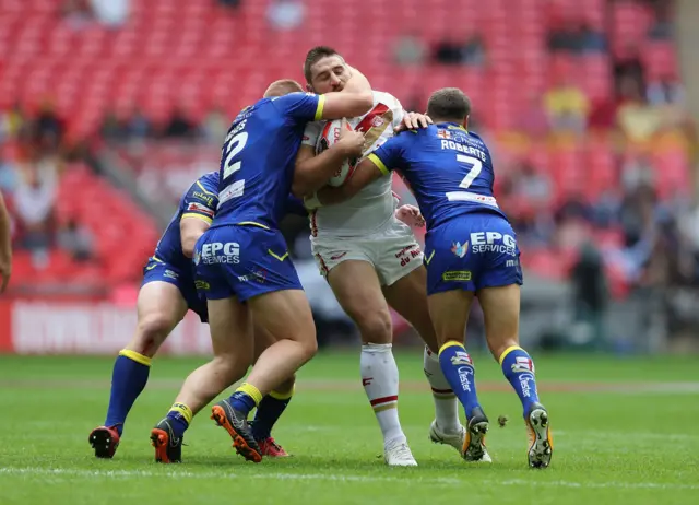 Julian Bousquet of Catalans Dragons is tackled by Jack Hughes, Chris Hill and Tyrone Roberts of Warrington