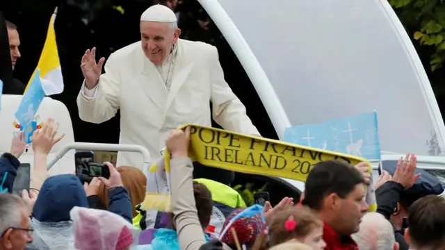 Pope Francis waves to the crowd as he travels in the popemobile to Knock shrine