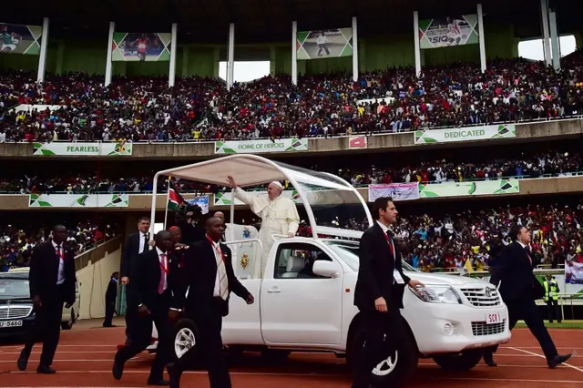 Pope Francis waves from his 'Popemobile' as he arrives at the Kasarani Stadium in Nairobi on November 27, 2015 for a meeting with youths