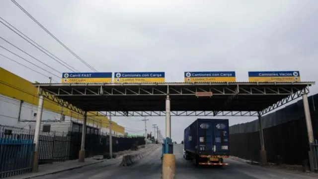 A truck drives next to the US/Mexico border fence