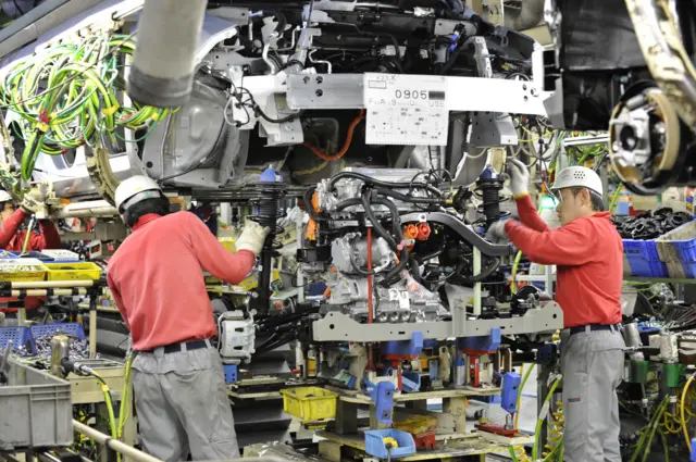 Nissan workers put in an engine into an electric car in 2011