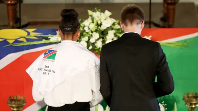 Two people before a coffin at the ceremony in Berlin, German