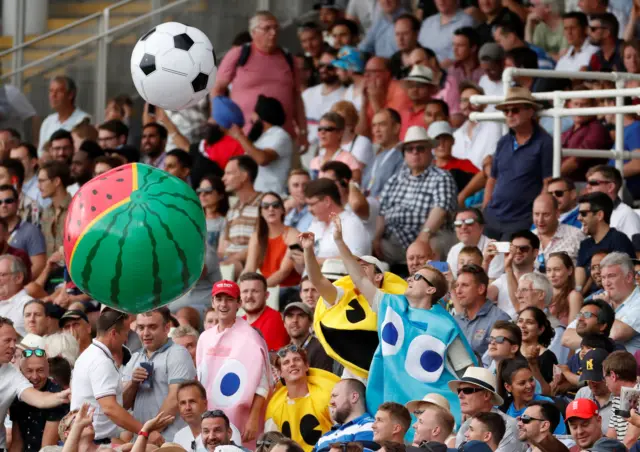 Fans in fancy dress play with inflatables