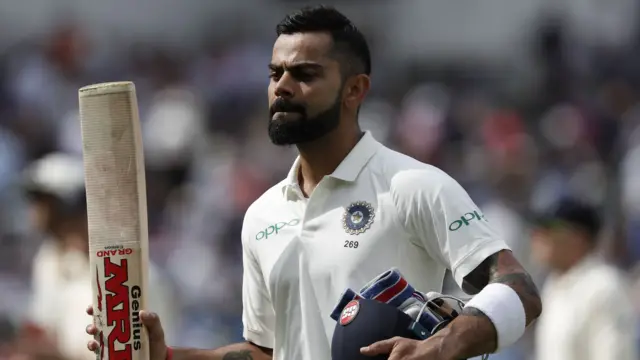 Virat Kohli raises his bat to acknowledge the crowd as he leaves the field