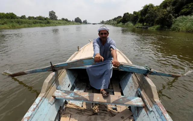 A farmer paddles his boat on the Nile river at Al-Giza