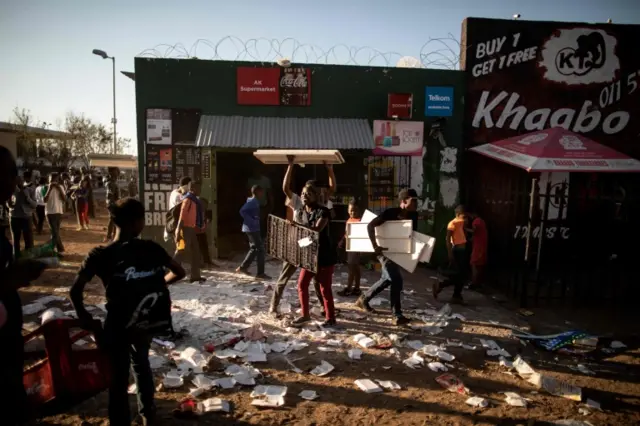 Looters take items from a foreign-owned shop in Soweto, Johannesburg, on August 29, 2018