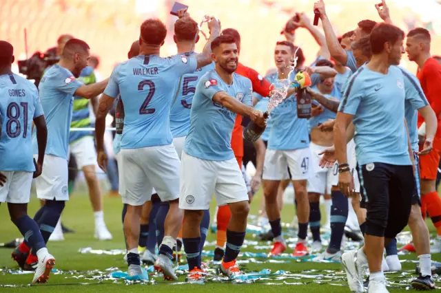 Sergio Aguero celebrates by spraying sparkling wine after the match