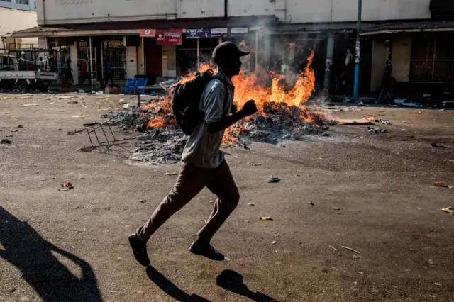 Protester running past a fire