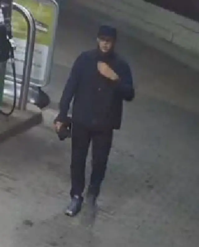 CCTV of a man wearing a hat and dark jacket with the collar up.