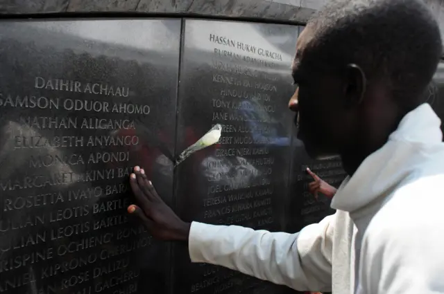 A man touches the memorial bearing the names of the dead in Nairobi