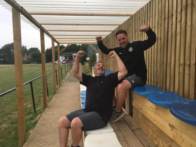 Club owner, Andy Dixon and his son sit in the makeshift wooden and plastic stand.