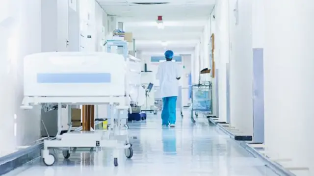 A person in scrubs walks down a hospital corridor