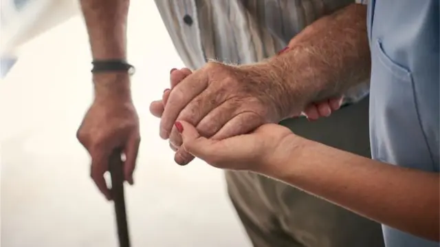 A carer holding someone's hand