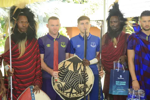 Former Everton player Wayne Rooney and current Everton team players Kevin Mirallas and Jonjoe Kenny  with Masaai Warriors during Everton’s visit to Tanzania last year.)