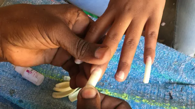 Fake nails being attached in Dar es Salaam