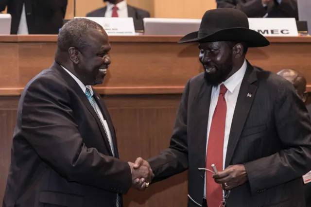 South Sudan"s President Salva Kiir (R) and his former deputy turned rebel leader Riek Machar (L) shake hands as they make a last peace deal