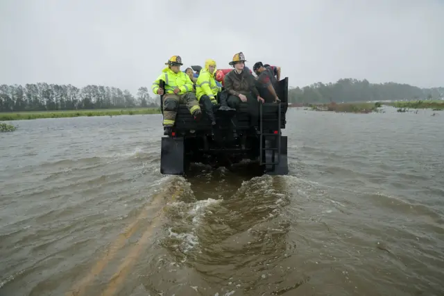 Rescue workers from Township No. 7 Fire Department and volunteers from the Civilian Crisis Response Team use a truck to move people rescued from their flooded homes