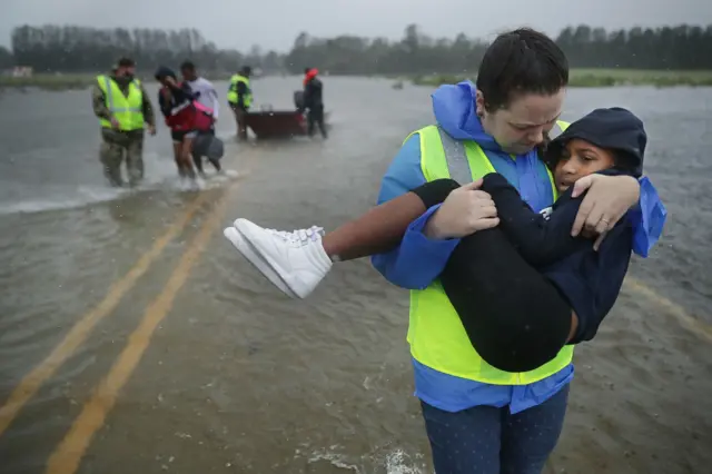 Volunteers from the Civilian Crisis Response Team help rescue three children from their flooded home