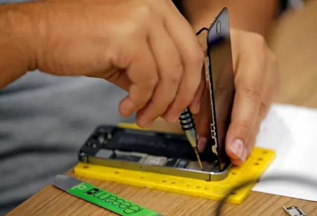 A technician repairs a cell phone in a repair shop