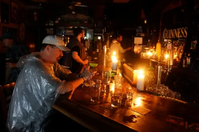 People sit at bar with candle light and drink