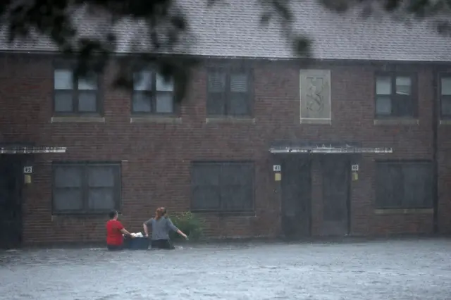 Women struggle with belongings in flood