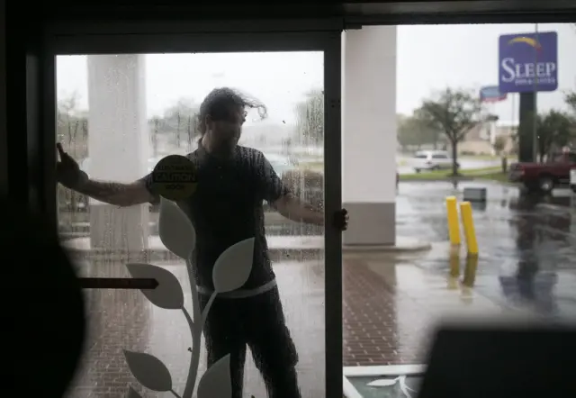 Jeremiah Johnson, a front desk clerk at the Sleep Inn in Jacksonville, North Carolina, attempts to reattach the front doors of the hotel