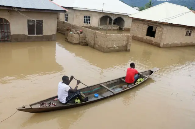 Residents steer a dugout canoe past flooded houses following heavy rain in the Nigerian town of Lokoja, in Kogi State, on September 14, 2018.