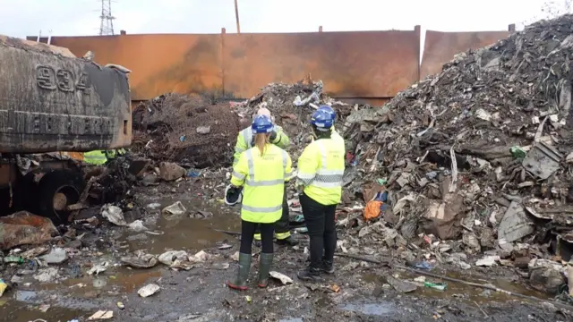 Four people stood in the recycling plant yard