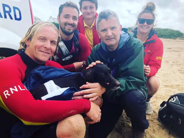 Lola and her owner with four RNLI lifeguards