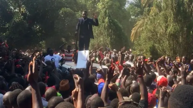 Bobi Wine addressing the crowds outside his home in Kampala, Uganda