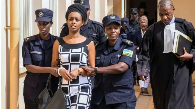 Diane Rwigara (C), a prominent critic of Rwanda's President Paul Kagame, is escorted by Police officers to the court room at the Nyarugenge intermediate court in Kigali on October 9, 2017