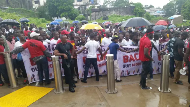 Protesters hold signs and join hands in Monrovia