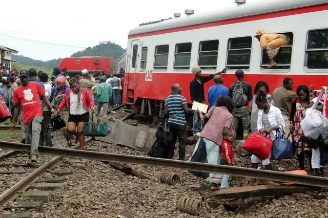 A passenger escapes a train car using a window as others leave from the site of a train derailment in Eseka on October 21, 2016