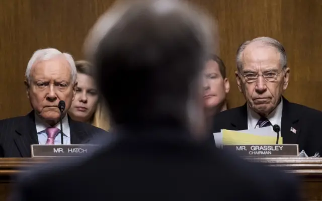 Senator Orrin Hatch (left) and Senator Chuck Grassley (right) listen as Brett Kavanaugh testifies.