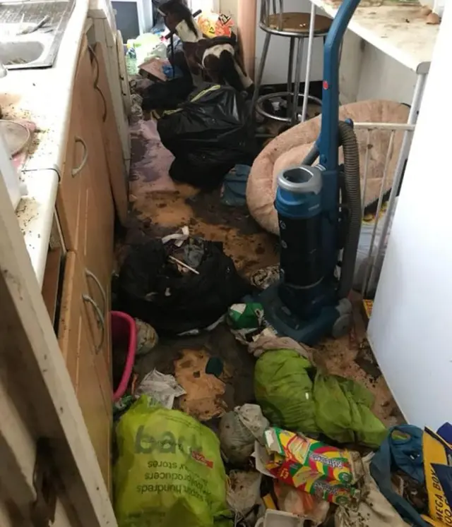 A kitchen filled with rubbish and with dirt everywhere.