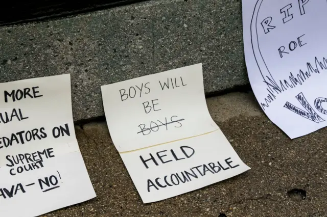 Protesters signs reading BOYS WILL BE BOYS/HELD ACCOUNTABLE, RIP ROE V WADE