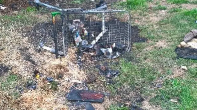 Charred shopping trolley on its side