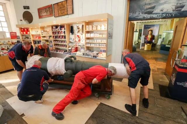 Workmen move the 42-pound cannon into position