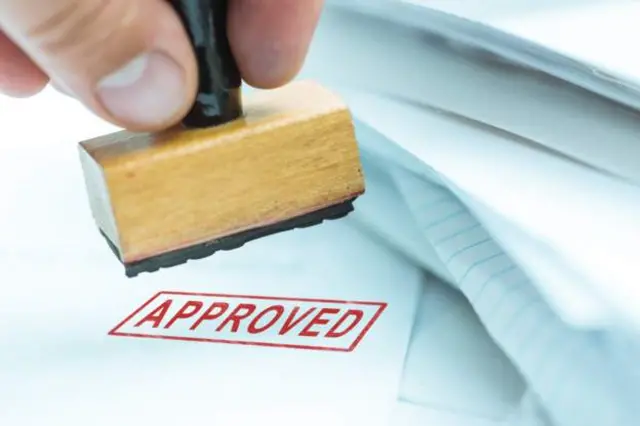 A document being stamped as 'Approved'