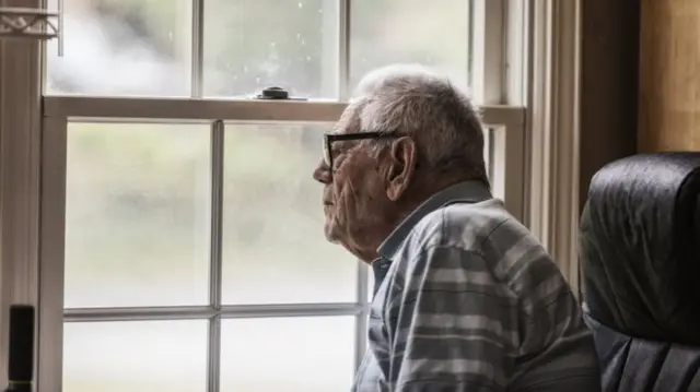 older man looking out a window