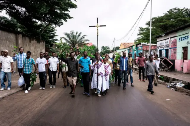 A man holds a Catholic cross as he takes part, with a group of Catholic faithfuls, in a demonstration outside the St Francois De Sales Church, during a protest called on by the Catholic Church, to push for the President of the Democratic Republic of the Congo, to step down on February 25, 2018 in Kinshasa