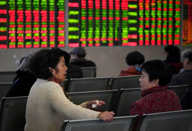 People sit in front of stock market boards in China