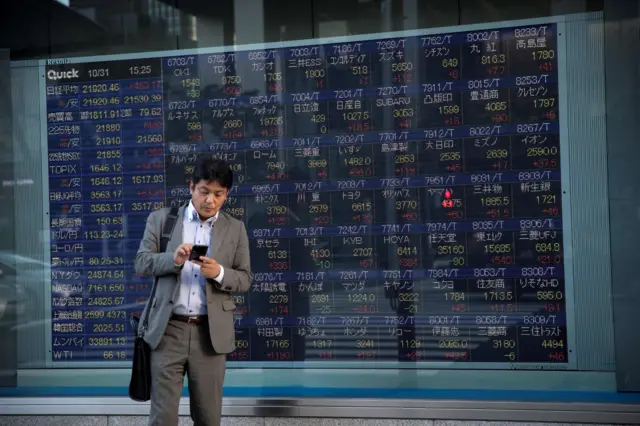 A man stands in front of stock market boards in Japan