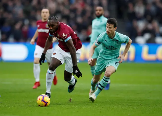 Michail Antonio runs at Laurent Koscielny