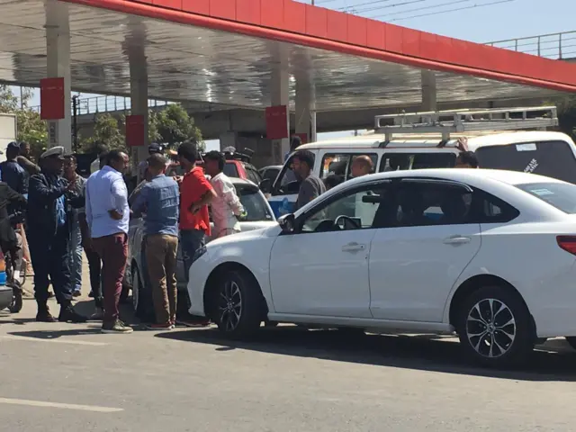 People standing in front of a fuel station