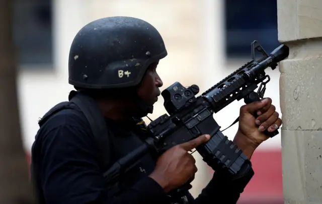 A member of security forces holds a weapon at the scene where explosions and gunshots were heard at the Dusit hotel compound, in Nairobi, Kenya January 15, 2019.