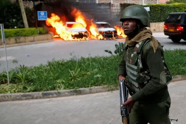 A policeman runs past burning cars at the scene where explosions and gunshots