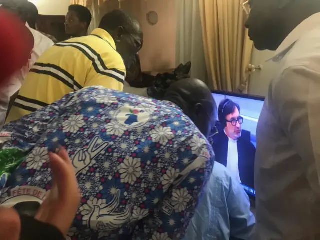 FPI party members crowd around a TV waiting for a ruling