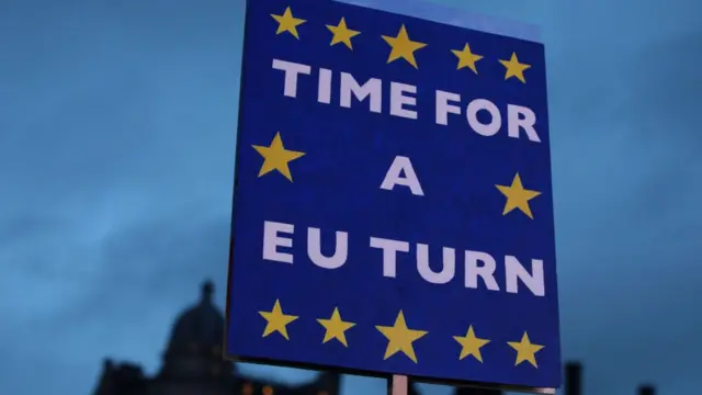 A placard reading 'Time For A EU Turn' is seen as protesters hold flags as they demonstrate on the day that MPs vote on Theresa May's Brexit deal